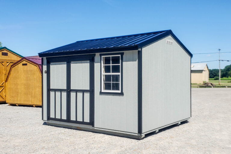 Rear and right-side view of the same 10x12 gray utility shed with black trim and blue metal gable roof, showing a solid wall and a single window.
