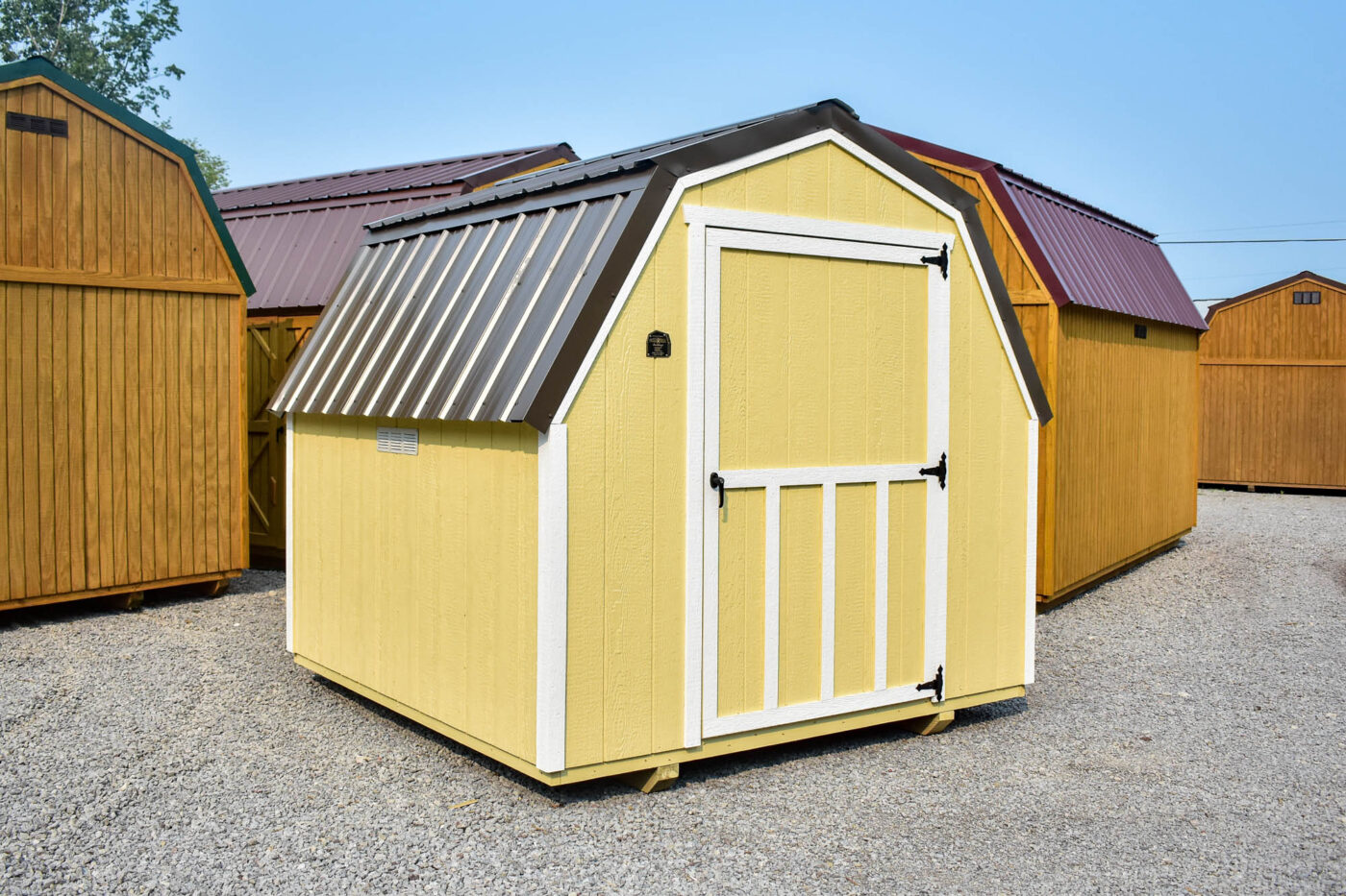 This compact 8x8 barn-style shed features soft yellow LP SmartSide® siding accented by clean white trim and a charcoal gray metal gambrel roof. The wide single door, framed with decorative battens, offers easy access to lawn equipment, tools, or garden supplies. Ideal for residential properties, this shed blends rustic charm with efficient, durable storage.