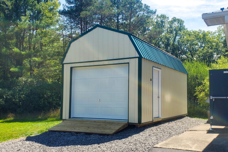 Pale yellow lofted garage shed - yellow metal siding with white side and overhead doors under green metal roof